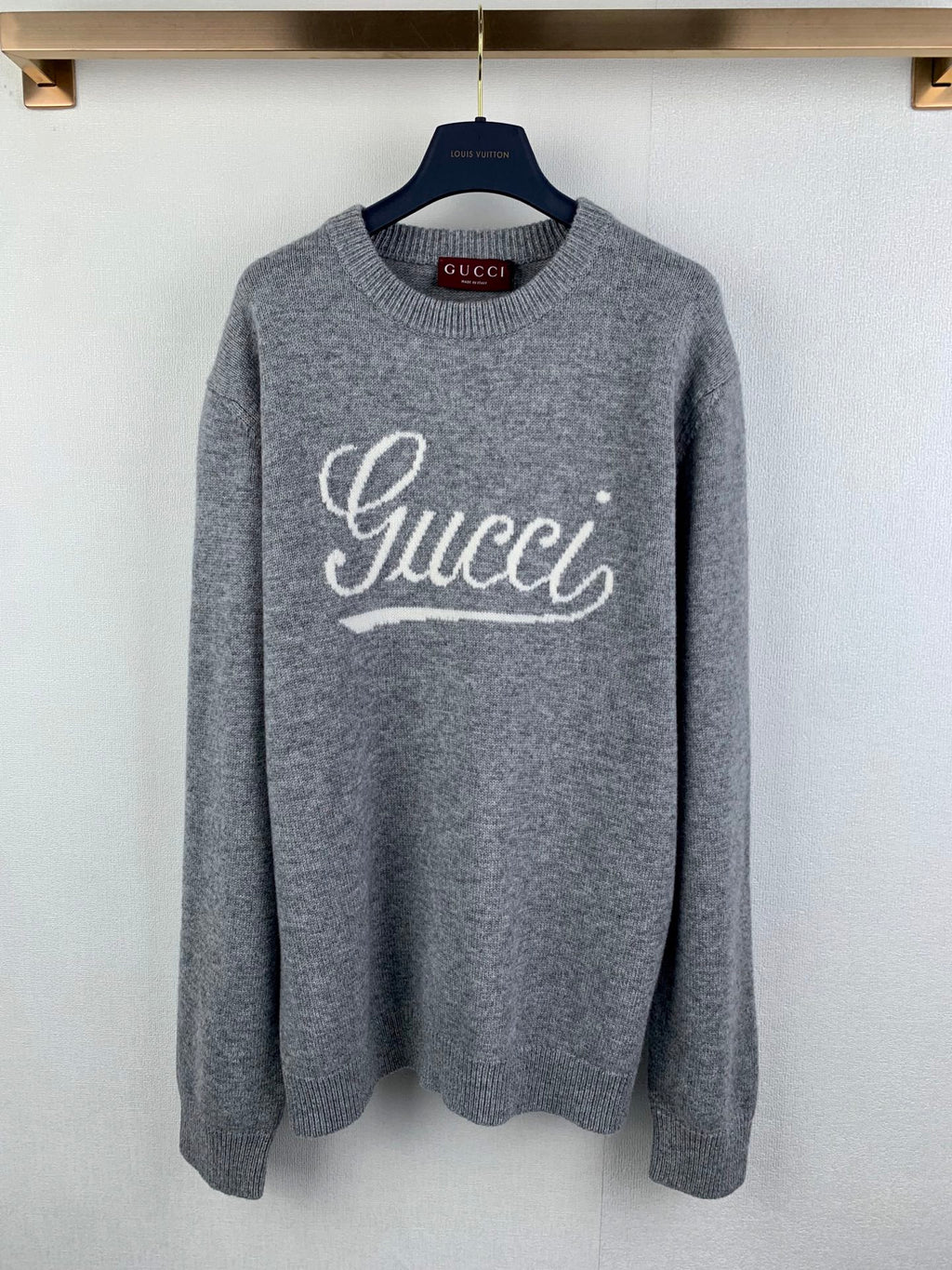 Gray knit crewneck sweater with large Gucci logo script on the chest