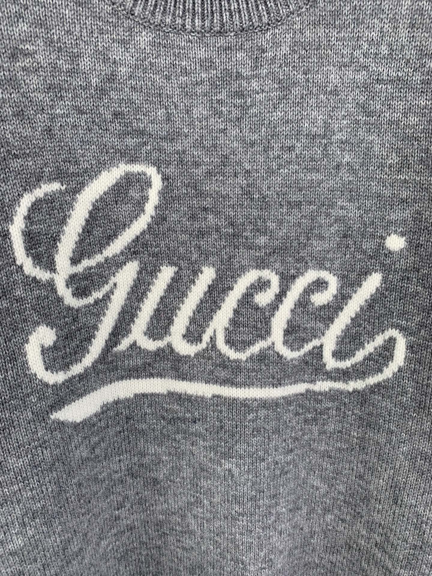 Gray knit sweater front with white Gucci script logo