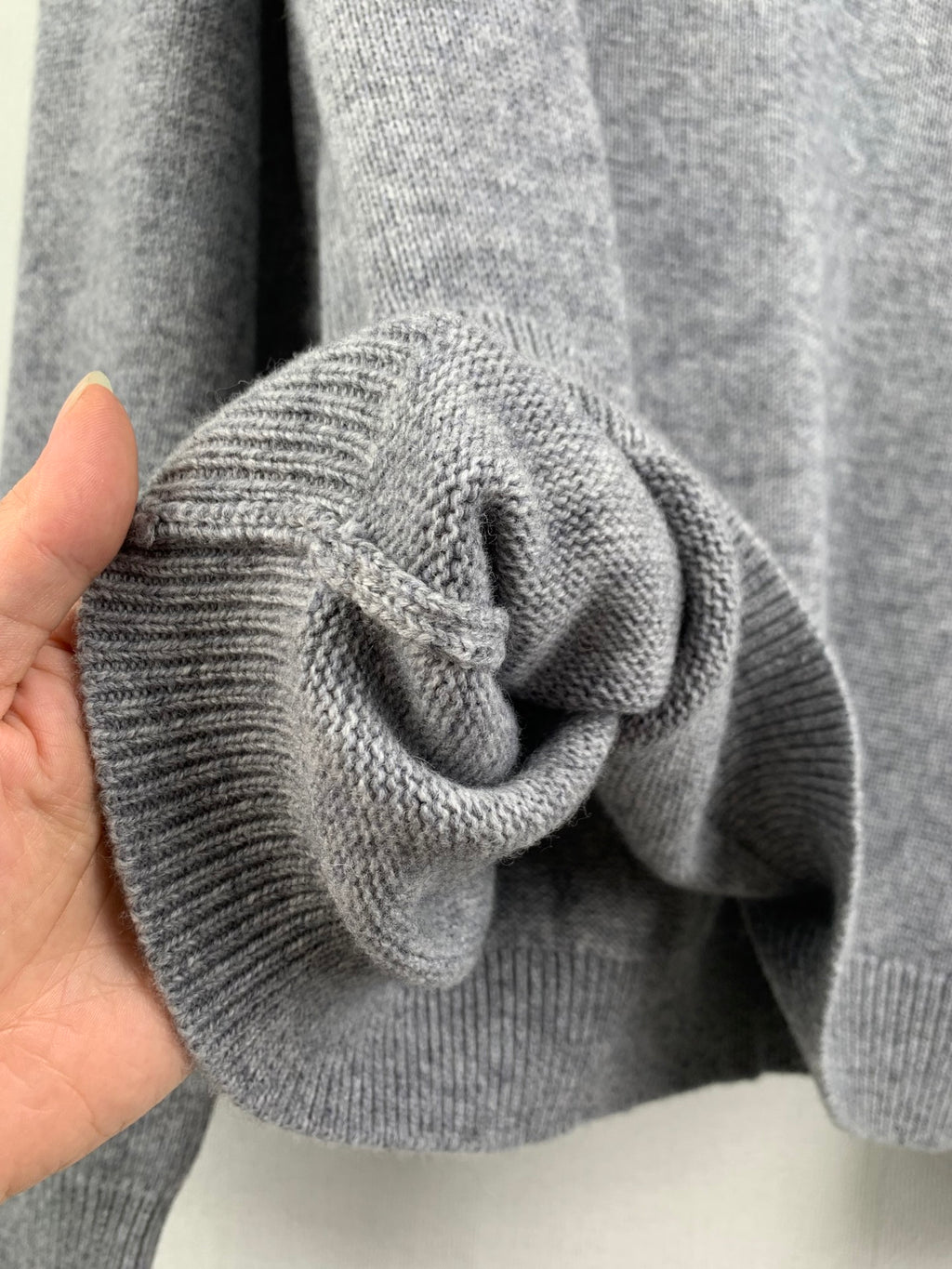 Gray knit sweater sleeve cuff with textured ribbed fabric