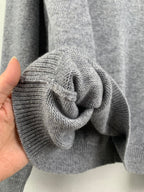 Gray knit sweater sleeve cuff with textured ribbed fabric