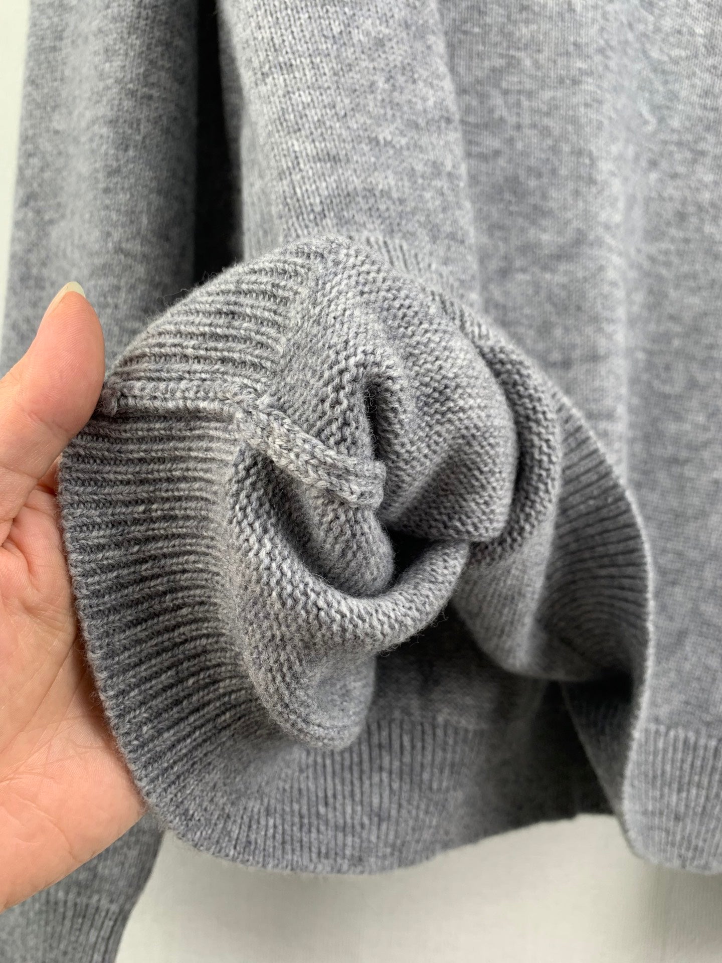 Gray knit sweater sleeve cuff with textured ribbed fabric