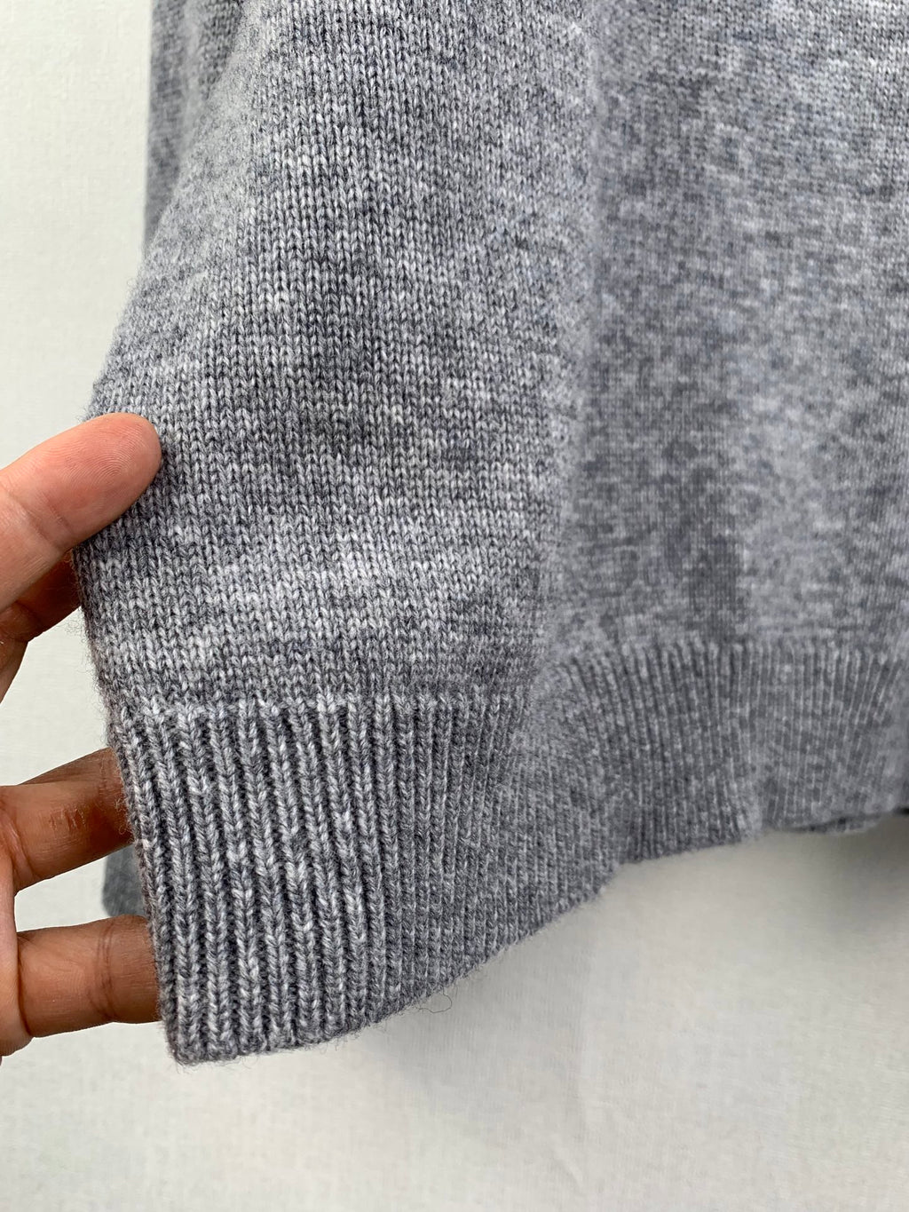 Gray knit sweater cuff and ribbed hem held in hand