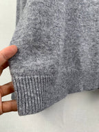 Gray knit sweater cuff and ribbed hem held in hand