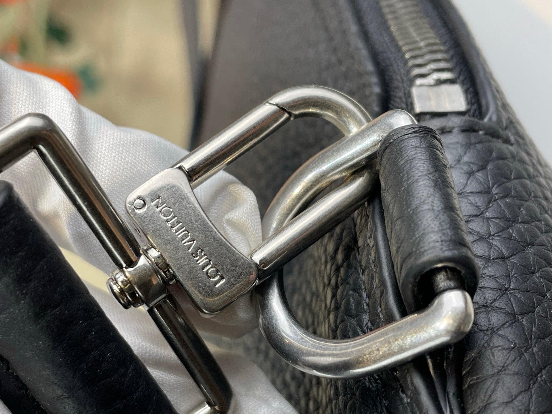 Louis Vuitton bag close-up of silver D-rings and strap attachment on dark leather