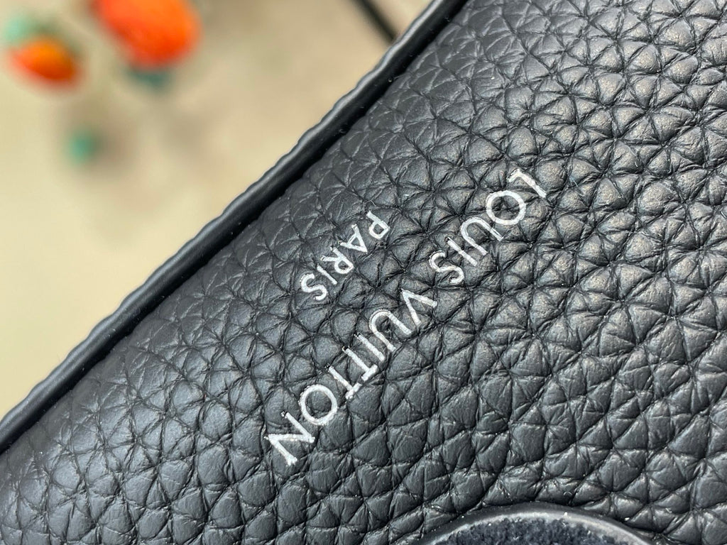 Louis Vuitton bag close-up of embroidered “Louis Vuitton Paris” logo on dark leather