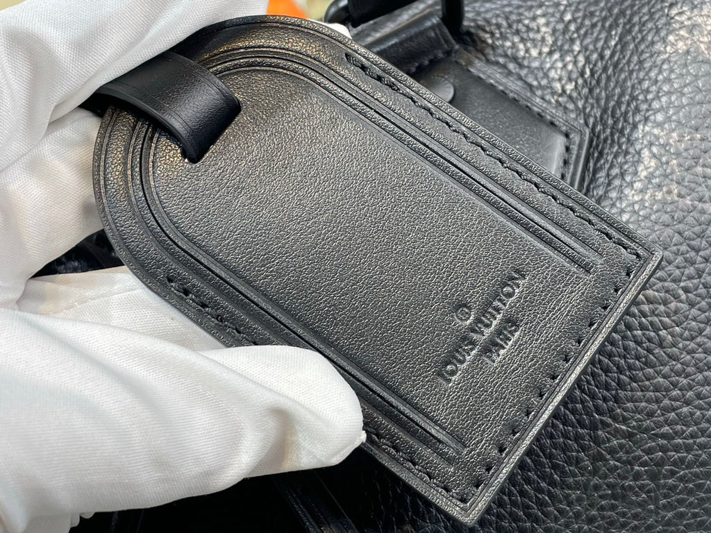 Black leather rectangular label with stitched edge and embossed logo on bag