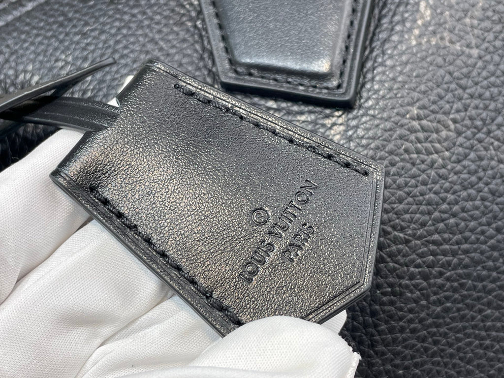 Black leather tag with debossed logo and stitched border on textured bag