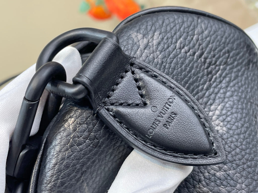 Black leather handle base with stitched tab and embossed logo on bag