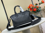 Black leather top-handle satchel bag with long crossbody strap and side charm