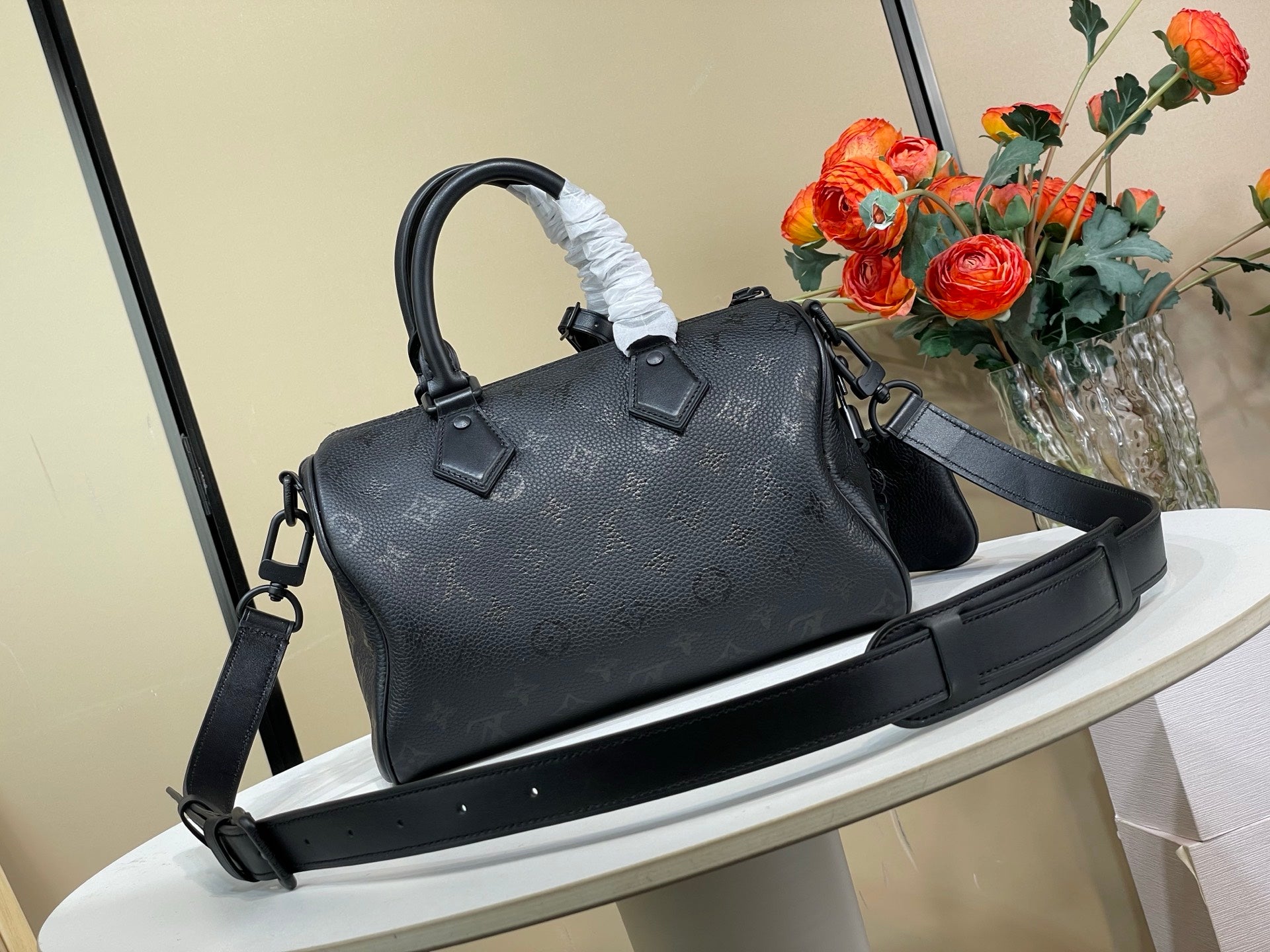 Black leather top-handle satchel bag with long crossbody strap and side charm
