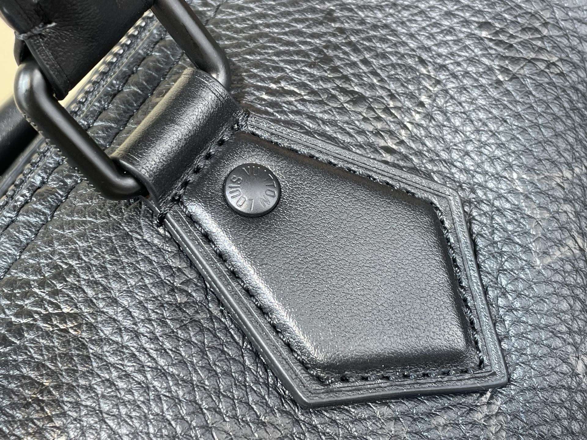 Black leather bag corner patch with snap closure on textured material