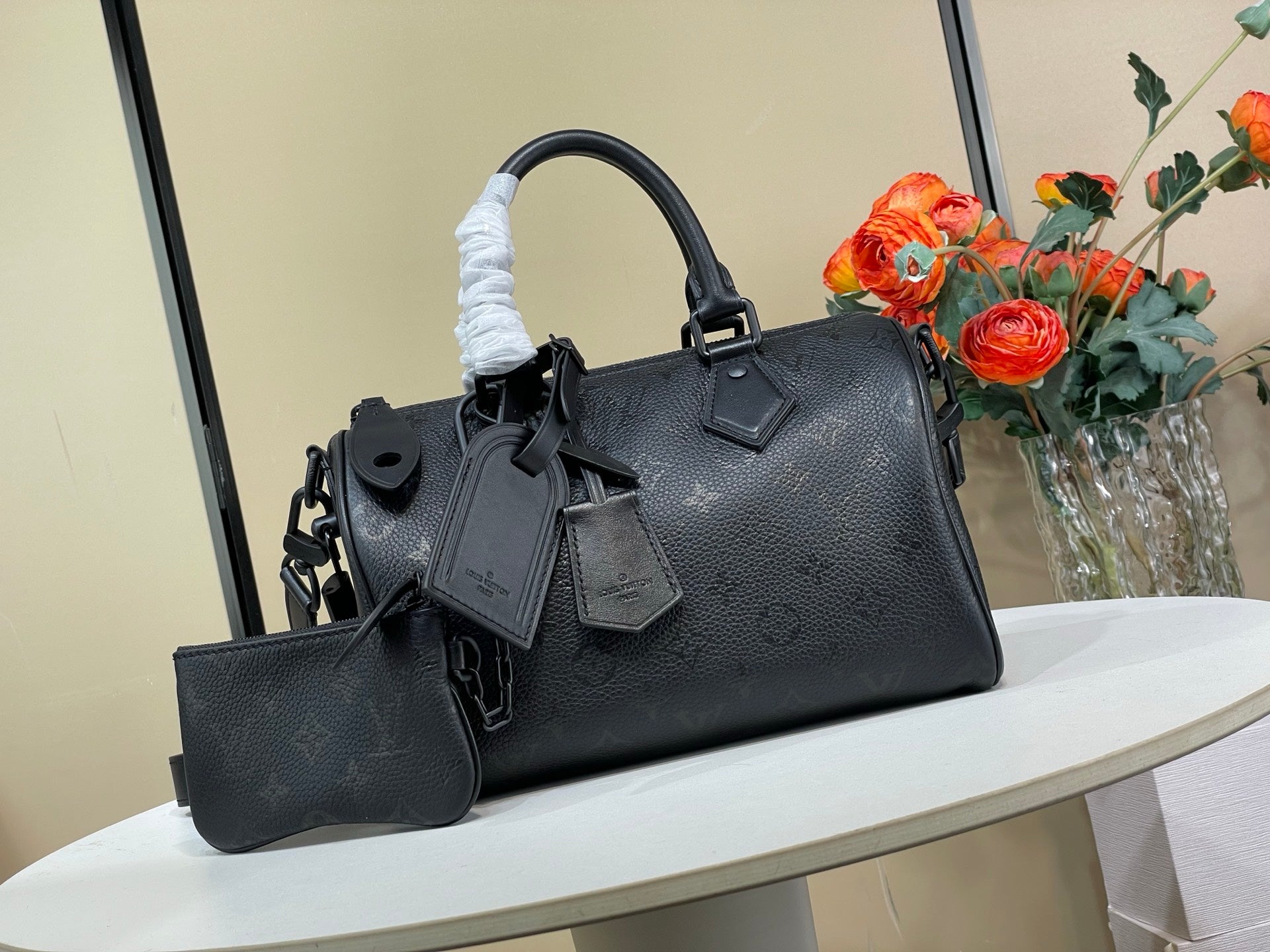 Black leather top-handle tote bag with shoulder strap and front charm accessories