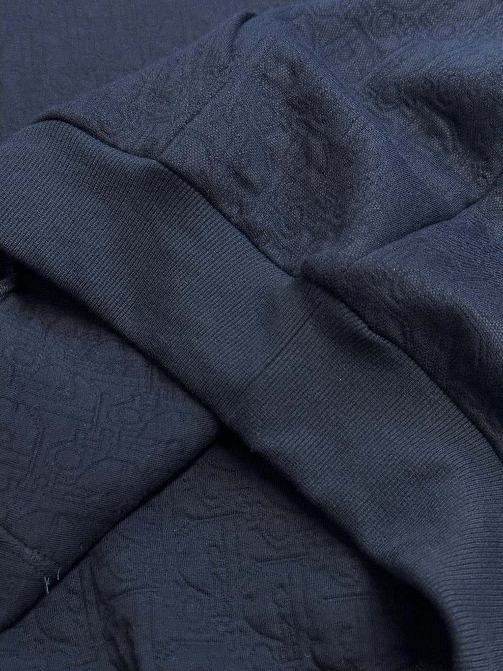 Navy blue hoodie fabric fold with textured embossed pattern