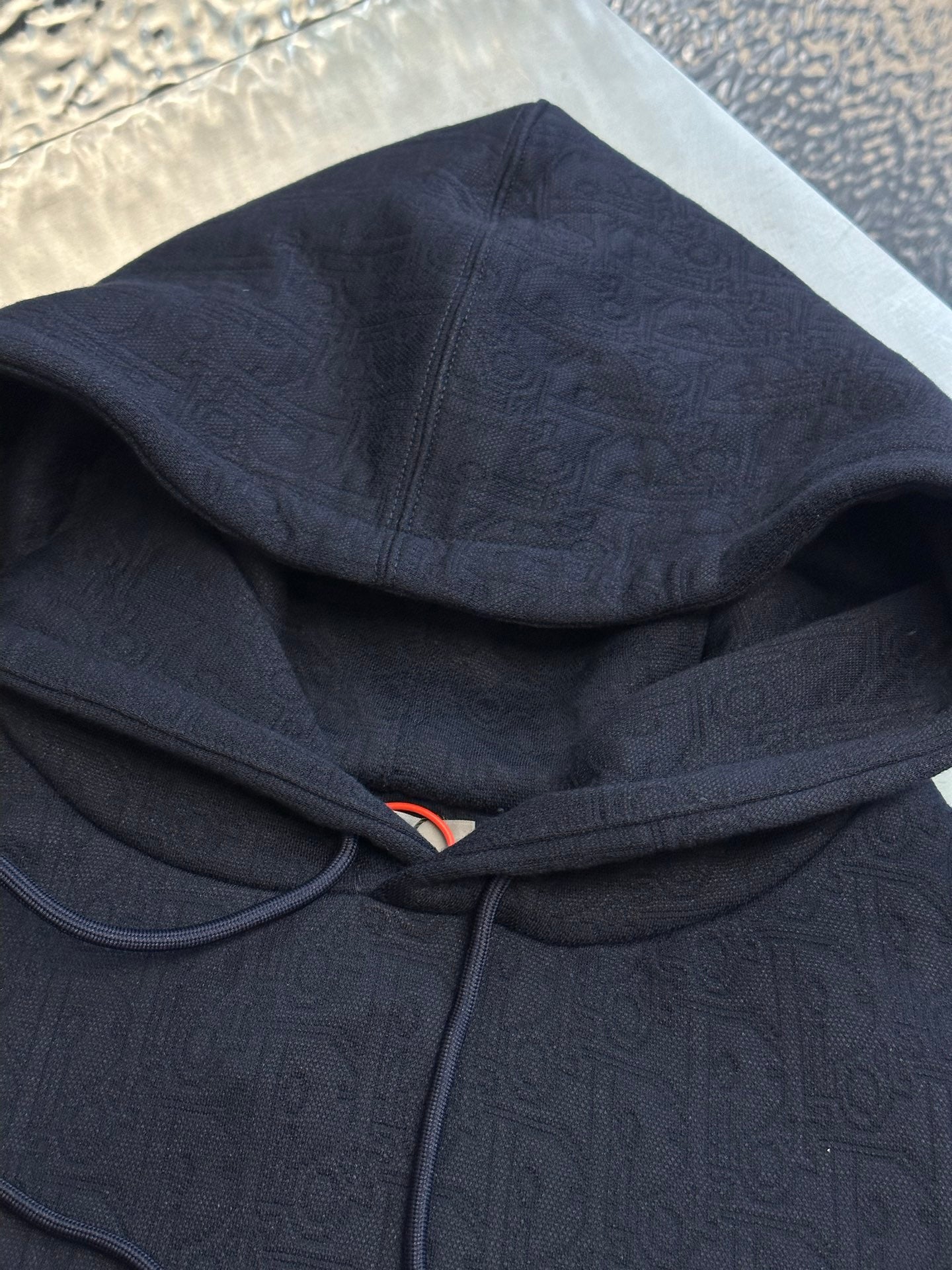 Navy blue zip hoodie close-up with drawcords and textured logo-like pattern