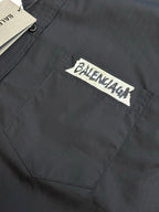 Dark charcoal button-up shirt chest pocket with rectangular Balenciaga logo patch