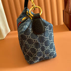 Gucci bag side view with gold ring attachment and blue GG canvas fabric.
