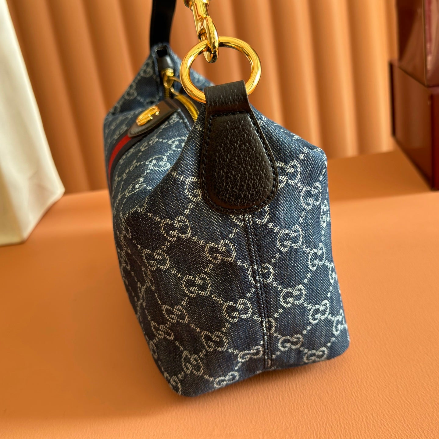 Gucci bag side view with gold ring attachment and blue GG canvas fabric.