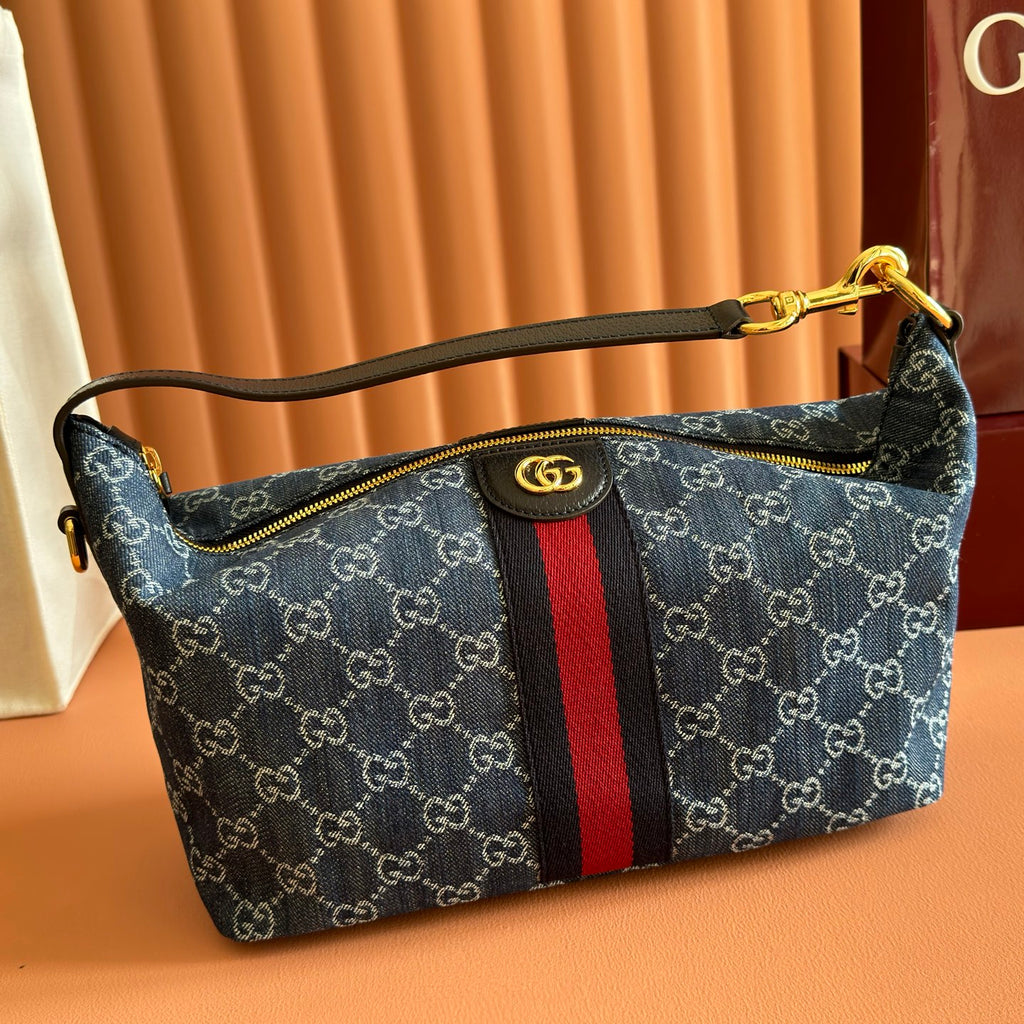 Gucci bag in blue GG canvas with red/black stripe, top zip and gold-tone handle hardware.