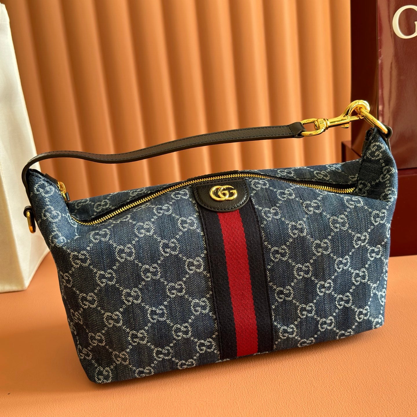 Gucci bag in blue GG canvas with red/black stripe, top zip and gold-tone handle hardware.