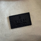 Gucci bag label: black embossed leather tag with Gucci text on beige lining.