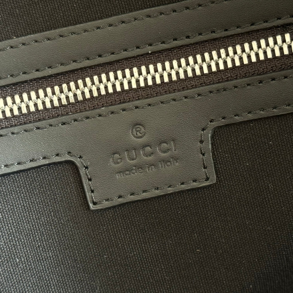 Gucci logo patch inside zippered compartment on dark duffel bag lining