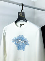 White sweatshirt close-up showing blue Versace logo graphic and crew neckline