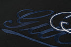 Close-up of blue embroidered Gucci script on black T-shirt