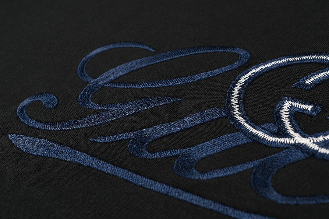 Close-up of blue embroidered Gucci script on black T-shirt