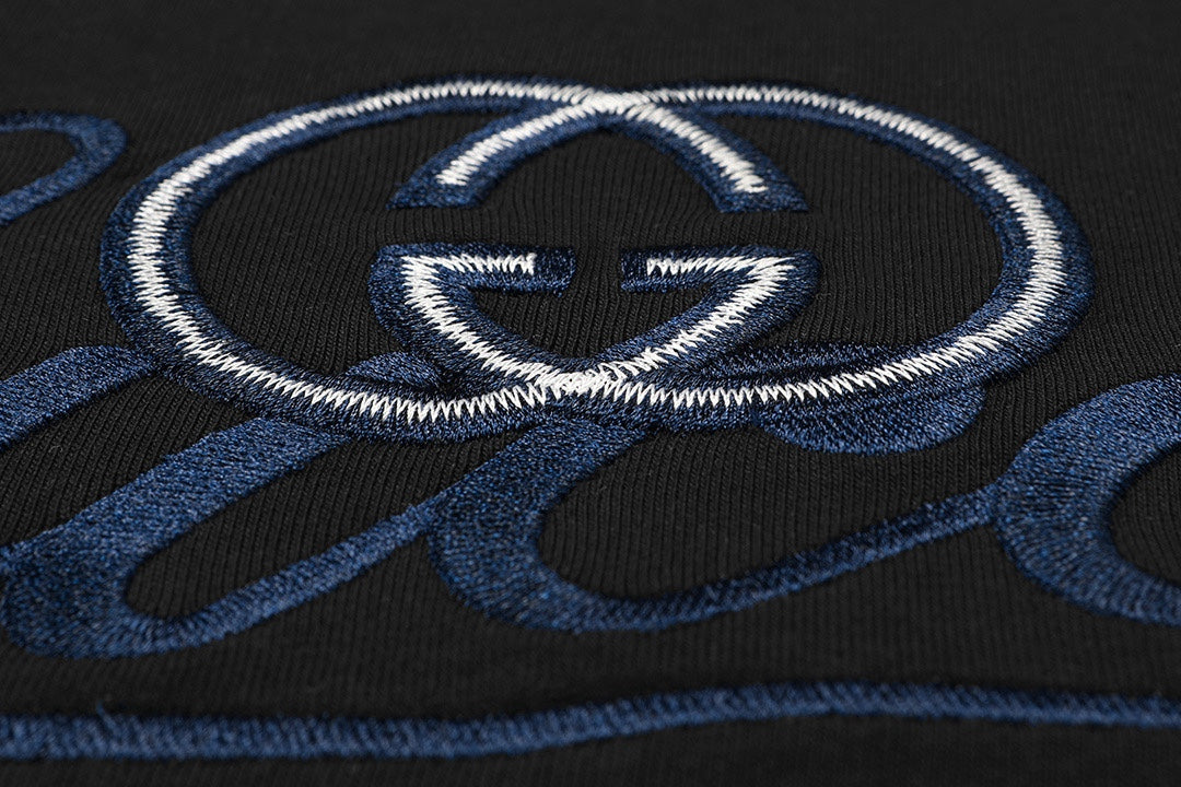 Close-up of blue-and-white Gucci emblem embroidery on black T-shirt