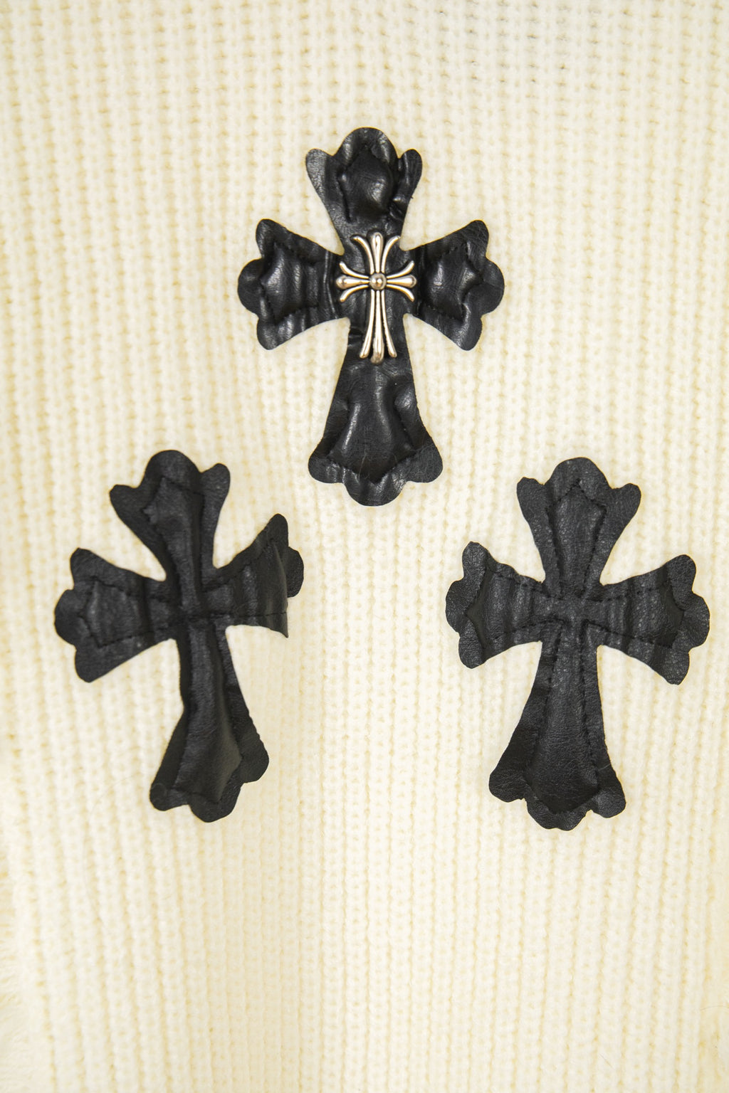Off-white knit sweater with three black clover cross applique details