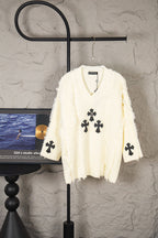 Off-white knit sweater with V-neck and black clover cross appliques