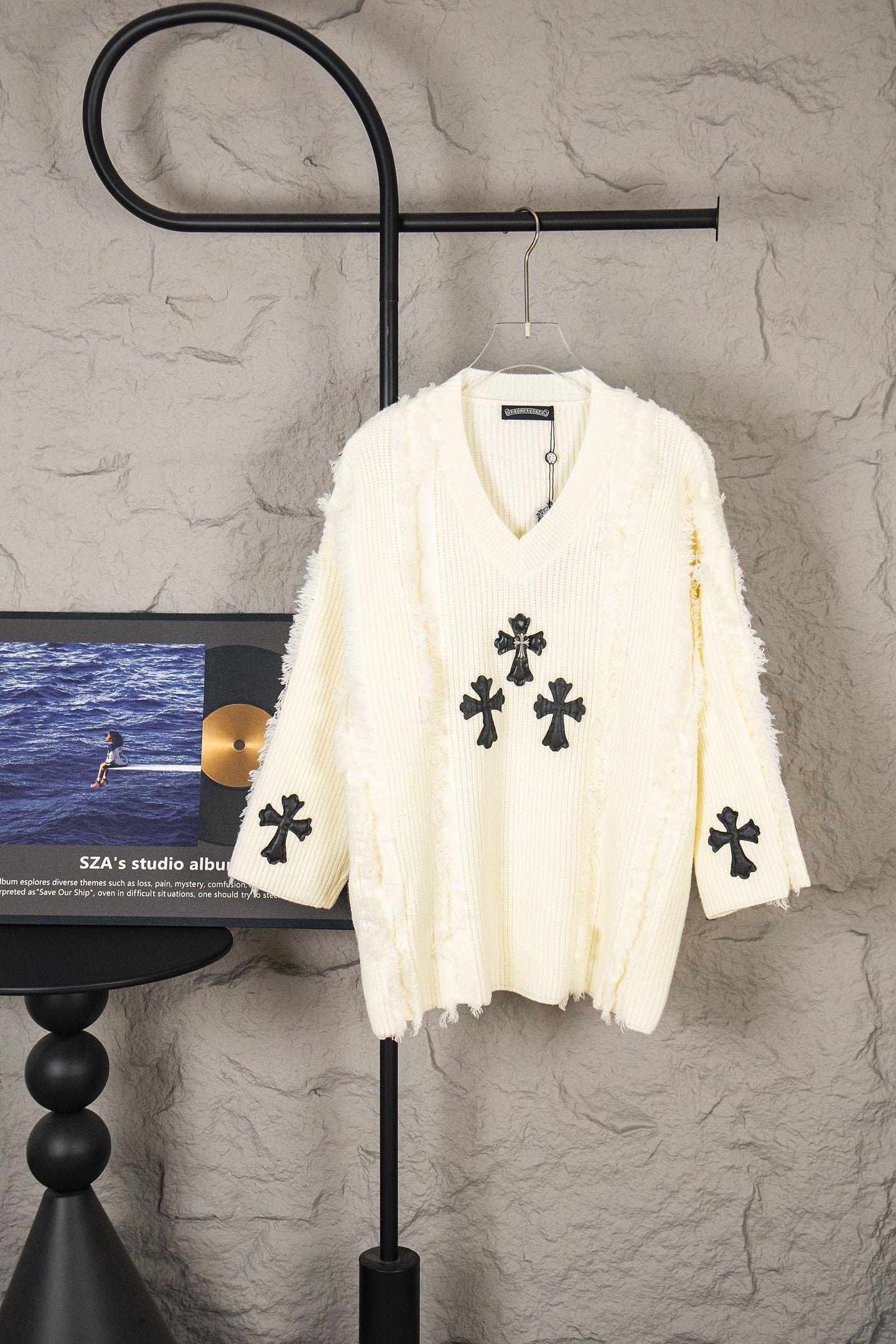 Off-white knit sweater with V-neck and black clover cross appliques
