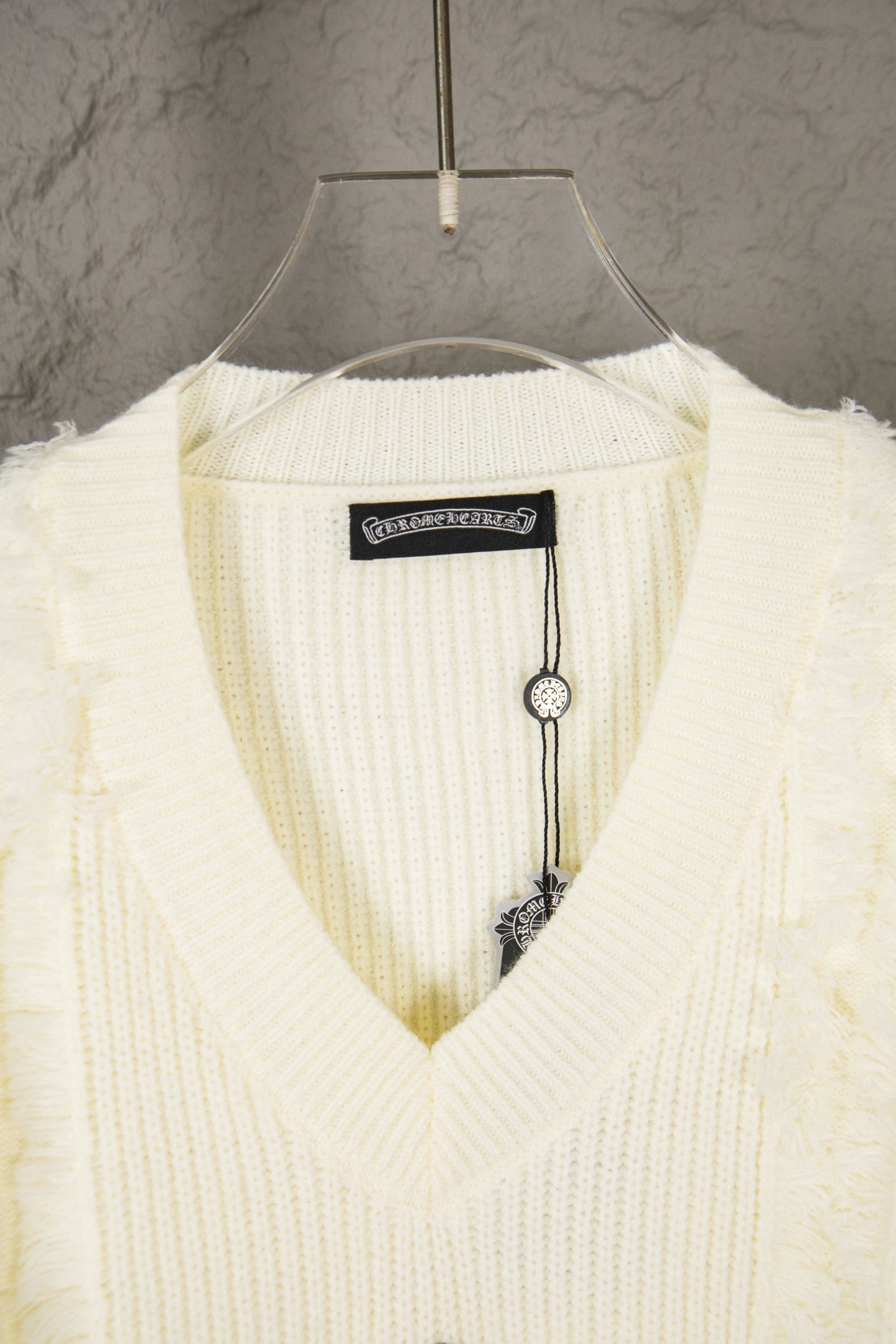Off-white V-neck knit sweater collar with brand label and hanging tag detail