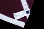 Burgundy T-shirt with white stripe and blue care label at the cuff