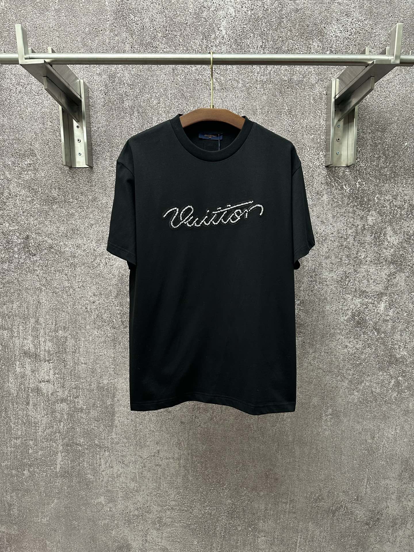 Dark T-shirt with crew neck, short sleeves, and white Louis Vuitton script on the chest