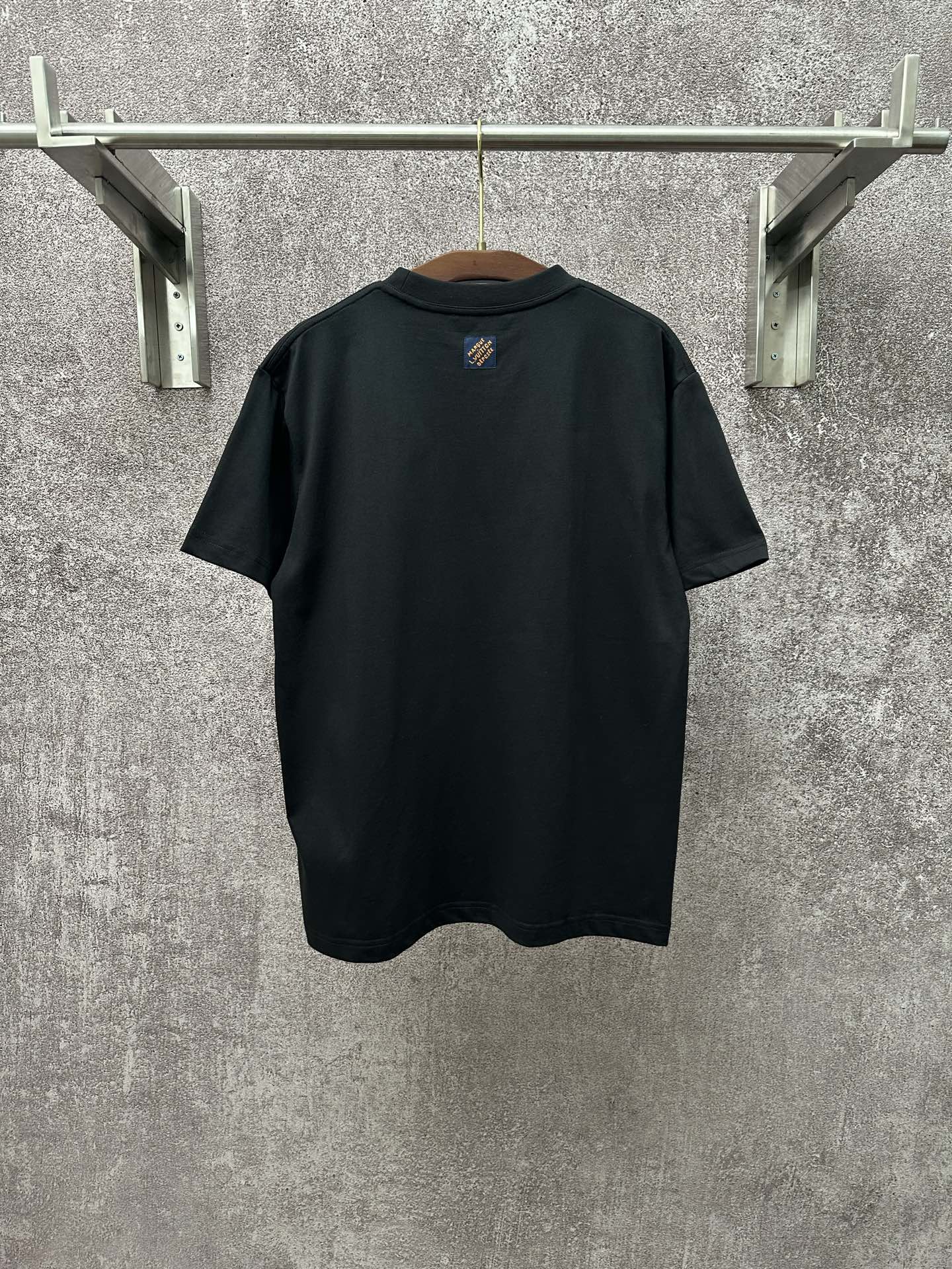 Dark T-shirt with crew neck and small crest logo at upper back
