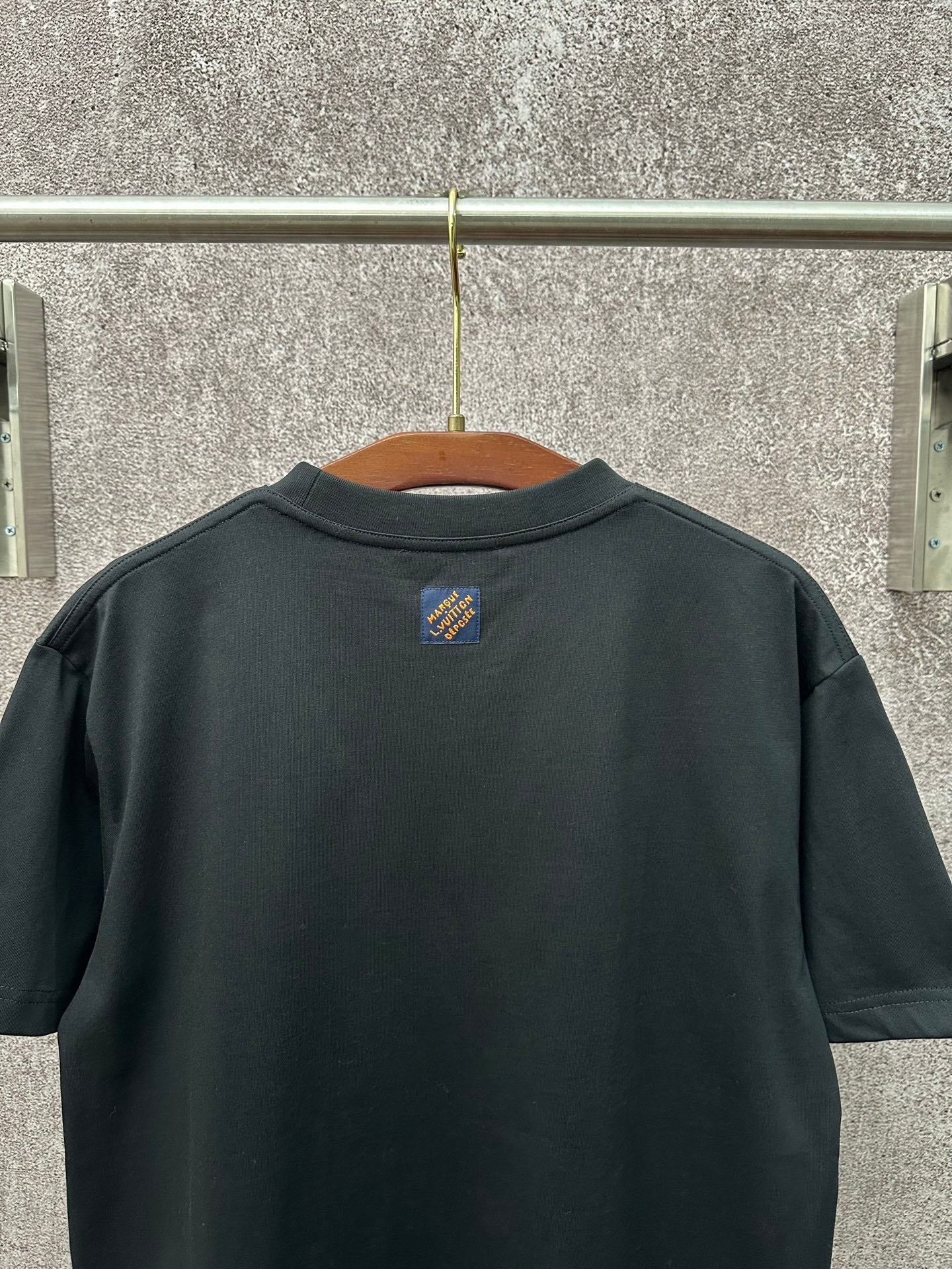 Dark T-shirt back view with small crest logo at upper center
