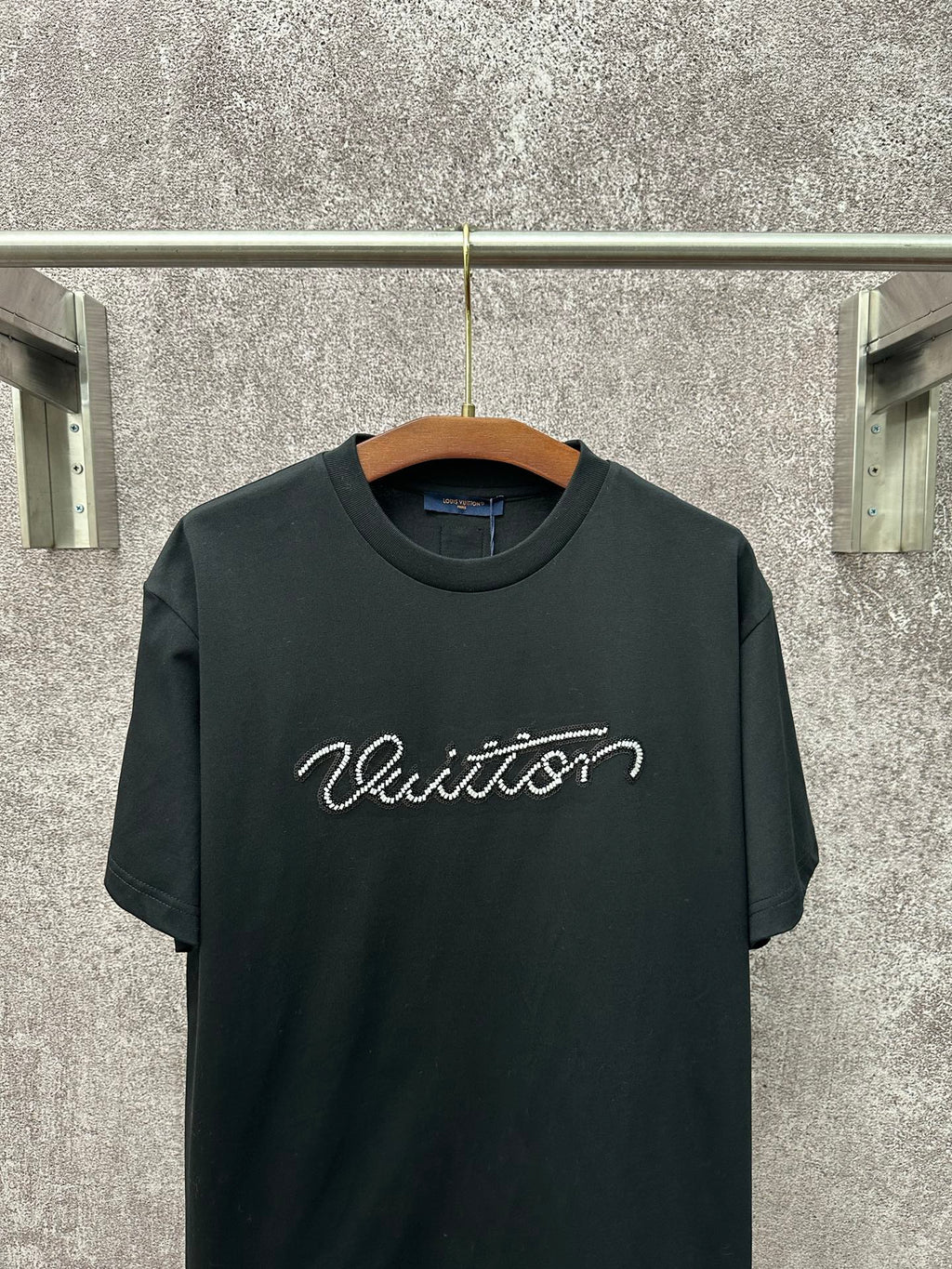 Dark T-shirt with crew neck and large white Louis Vuitton script across the chest