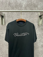 Dark T-shirt with crew neck and large white Louis Vuitton script across the chest