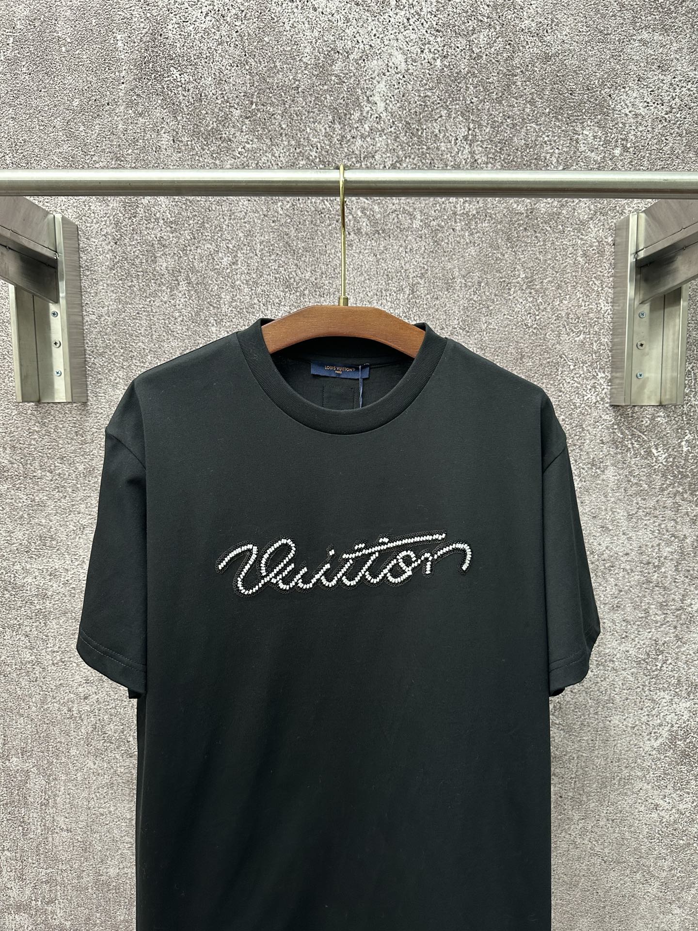 Dark T-shirt with crew neck and large white Louis Vuitton script across the chest