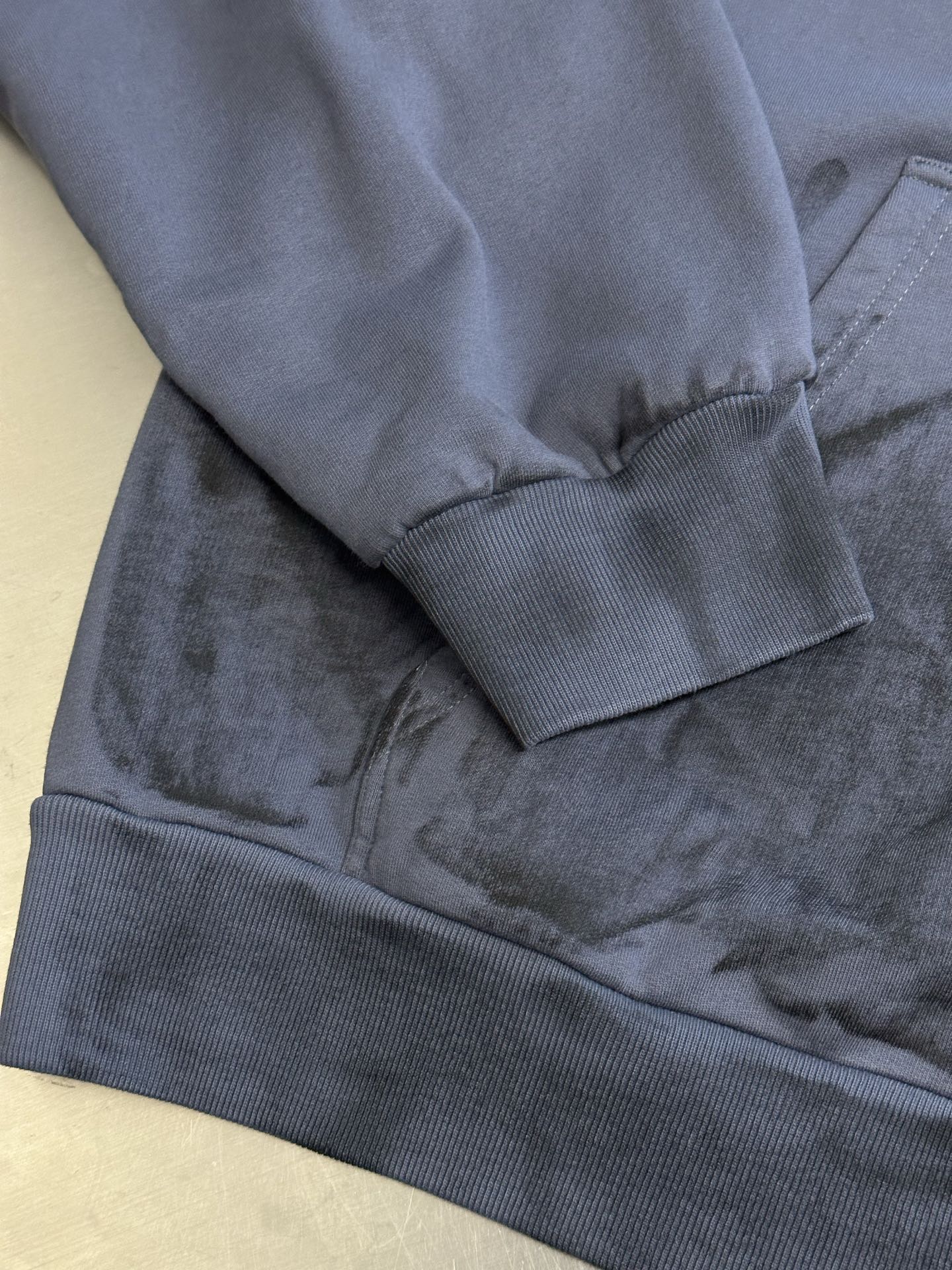 Light blue hoodie close-up of ribbed cuffs and hem with pocket seam detail
