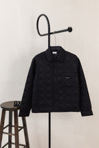 Black quilted long-sleeve jacket with stand collar and zip front, on hanger