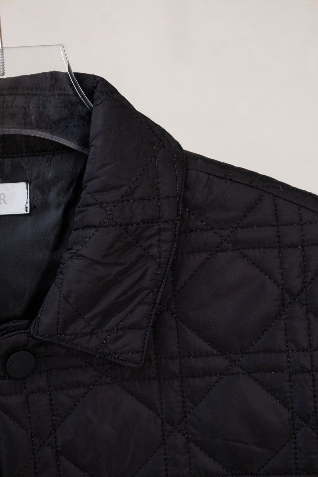 Black quilted jacket shoulder with button detail and angled front panel