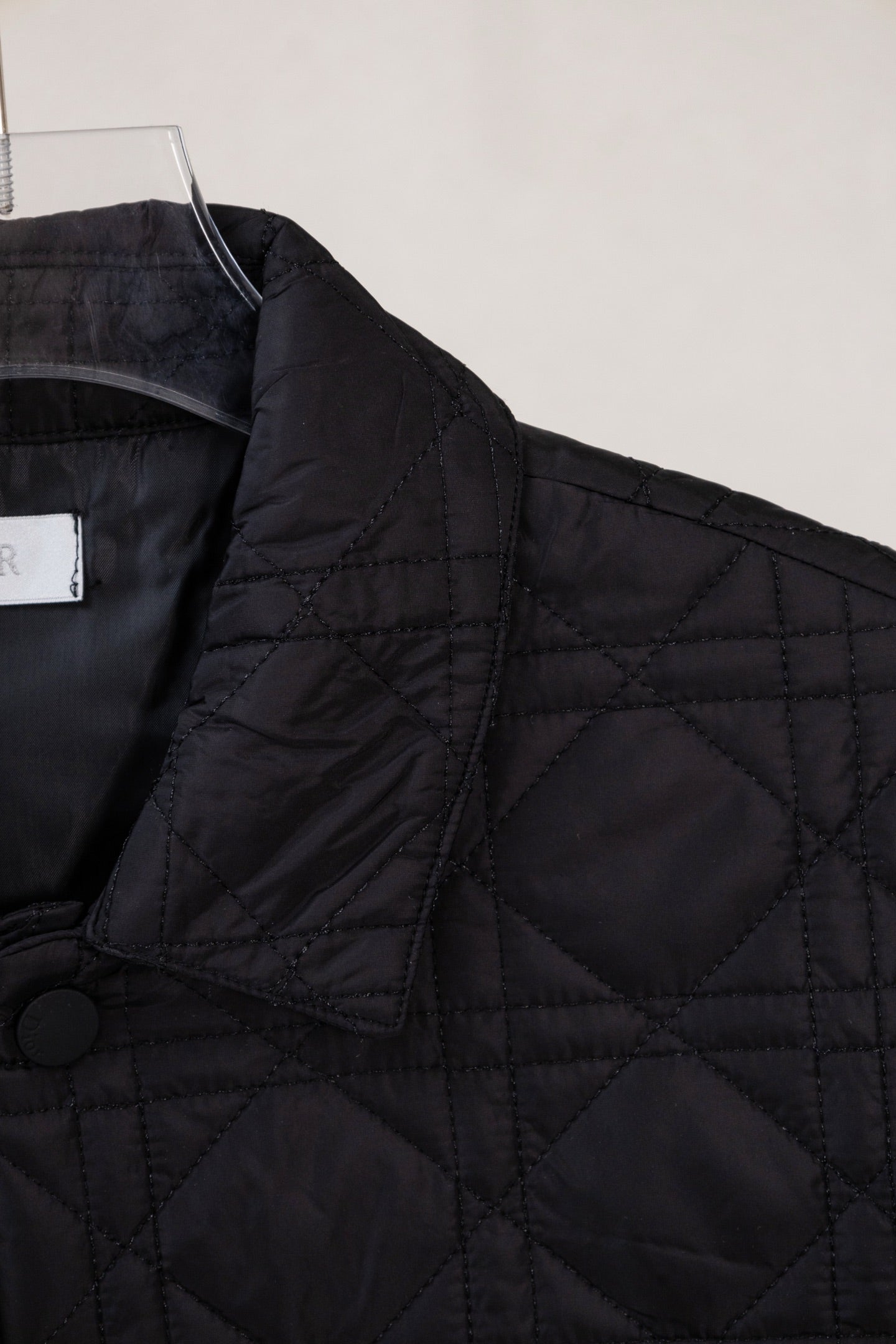 Black quilted jacket shoulder with button detail and angled front panel