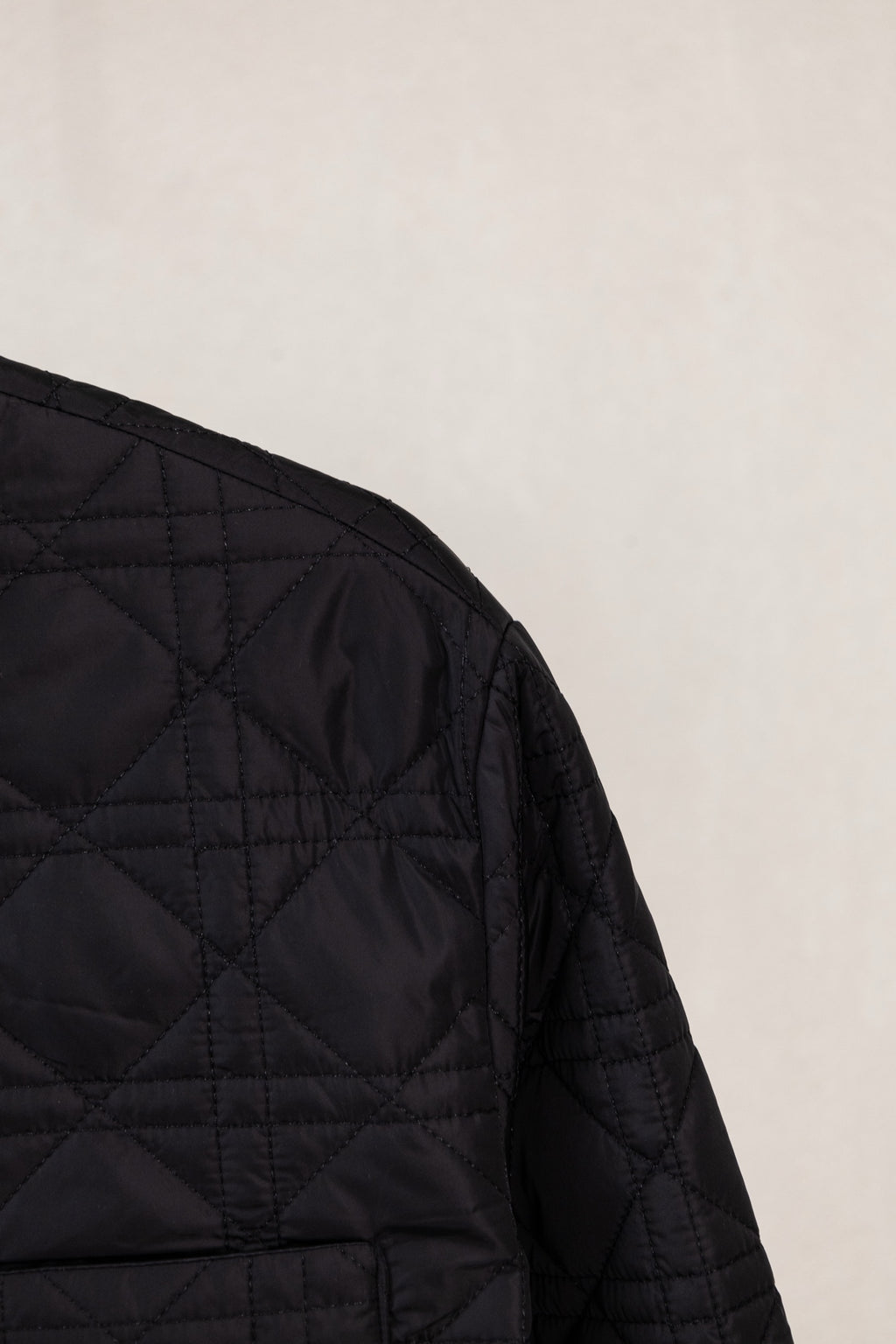Black quilted jacket side panel with diamond stitching and seam lines