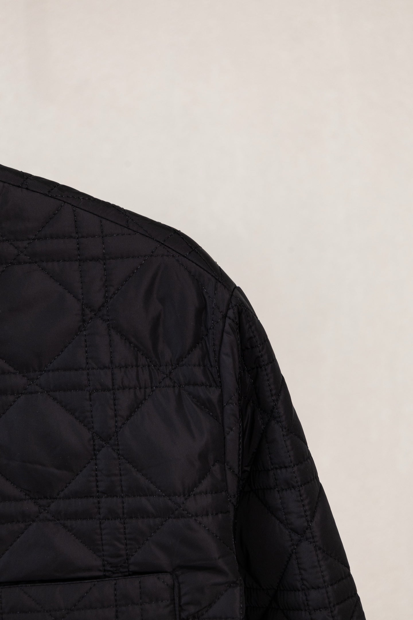Black quilted jacket side panel with diamond stitching and seam lines