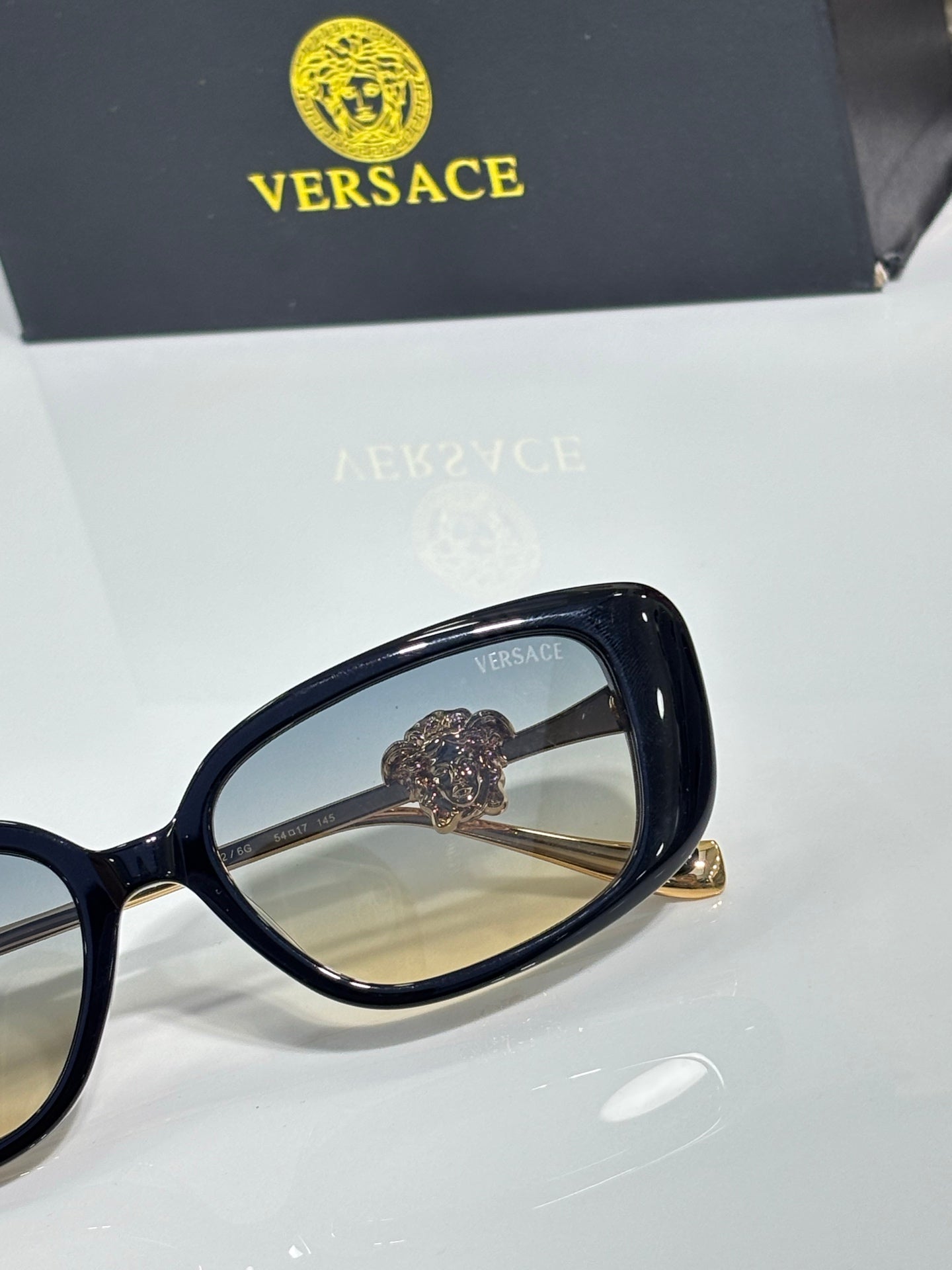 Versace black sunglasses close-up of gold-tone bridge and temple emblem