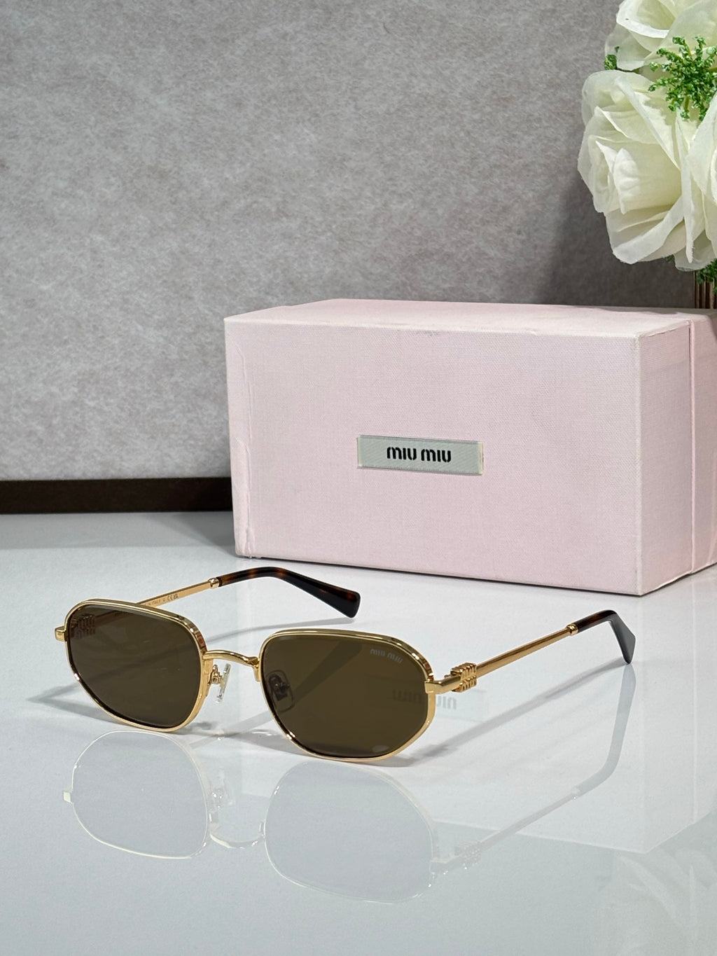 Gold metal sunglasses with dark lenses, round cat-eye shape, black temple tips