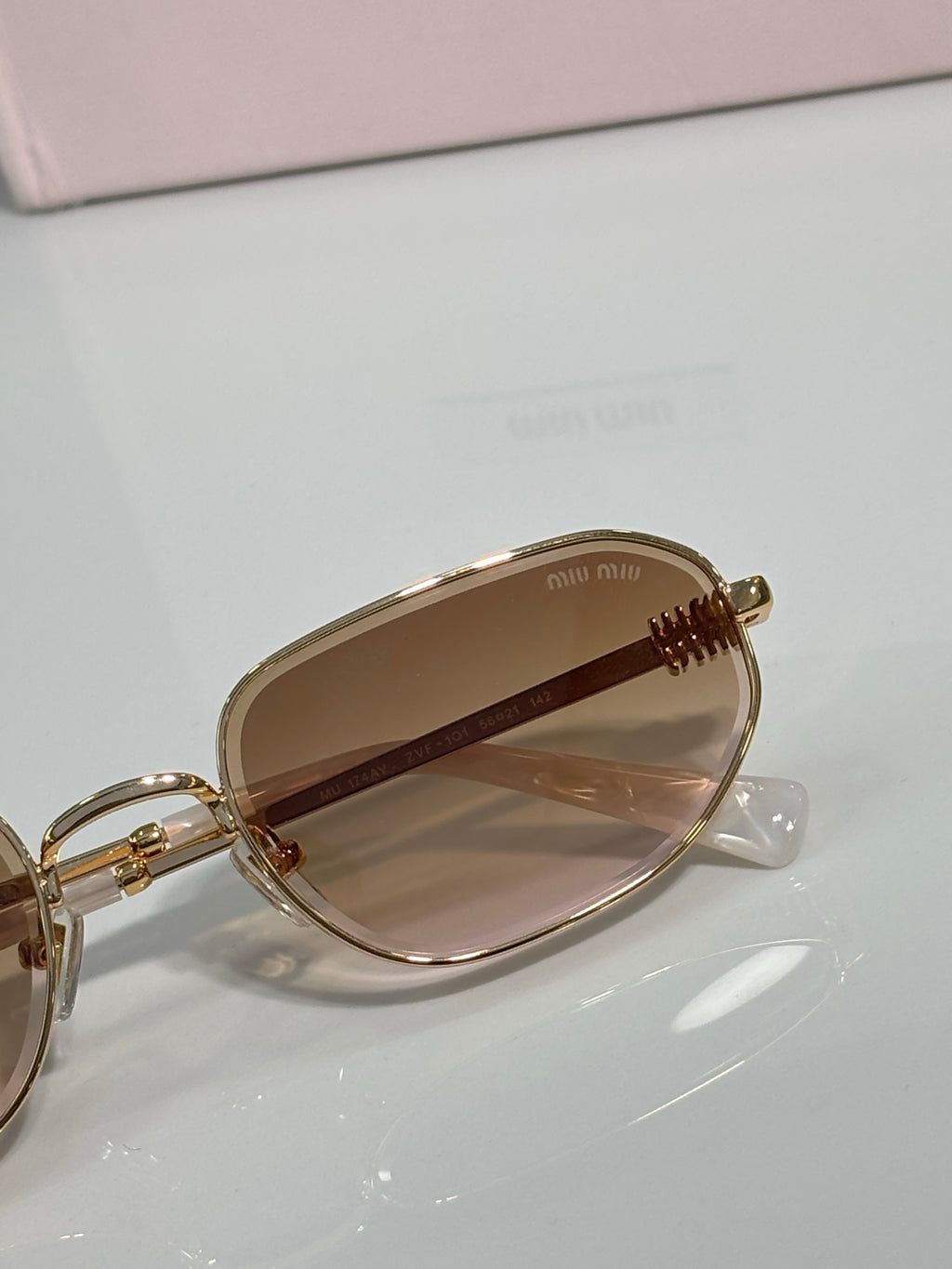 Gold sunglasses showing temple hinge and amber-tinted lenses, round cat-eye frame