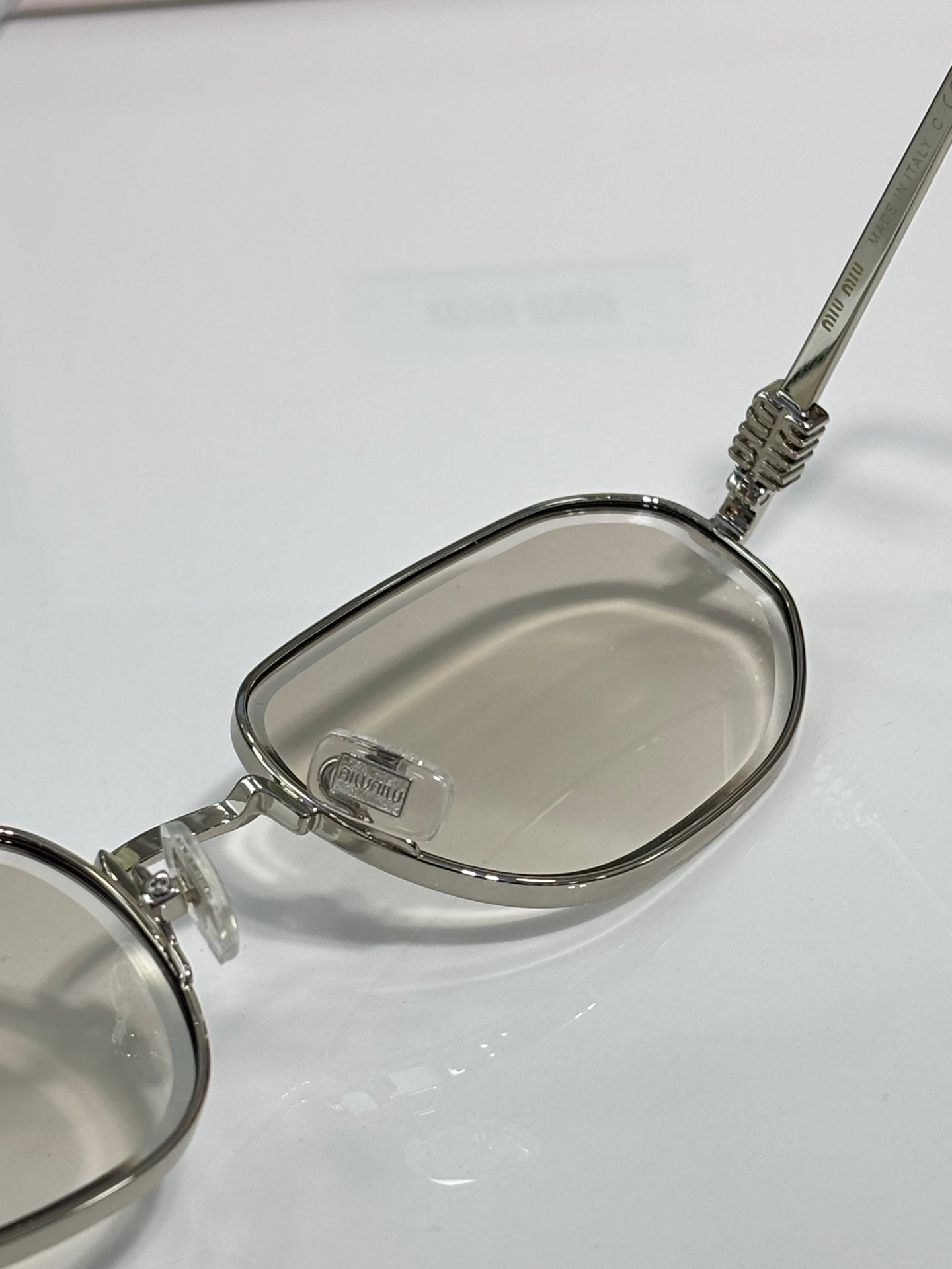 Silver metal sunglasses close-up with clear lenses and patterned temple hinge